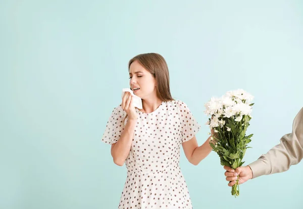 Man giving flowers to young woman suffering from allergy on light background — Stock Photo, Image