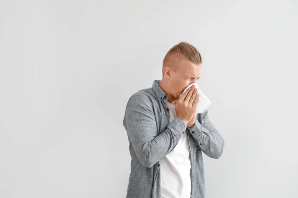 Young man suffering from allergy on light background — Stock Photo, Image
