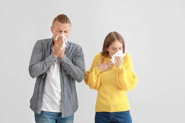 Casal jovem que sofre de alergia em fundo claro — Fotografia de Stock