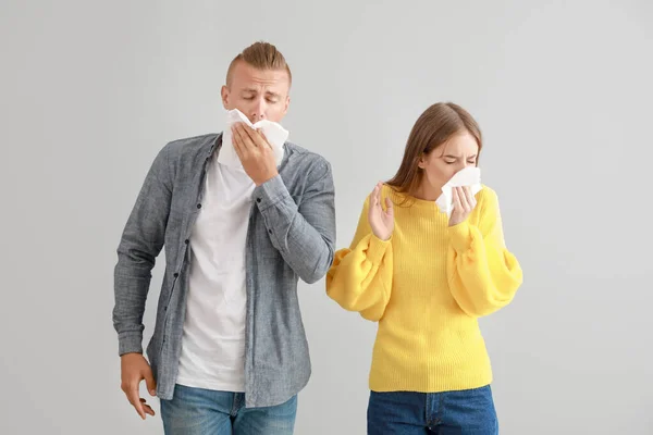 Casal jovem que sofre de alergia em fundo claro — Fotografia de Stock