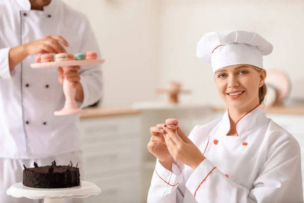 Pastelera femenina con sabroso macaron en la cocina — Foto de Stock