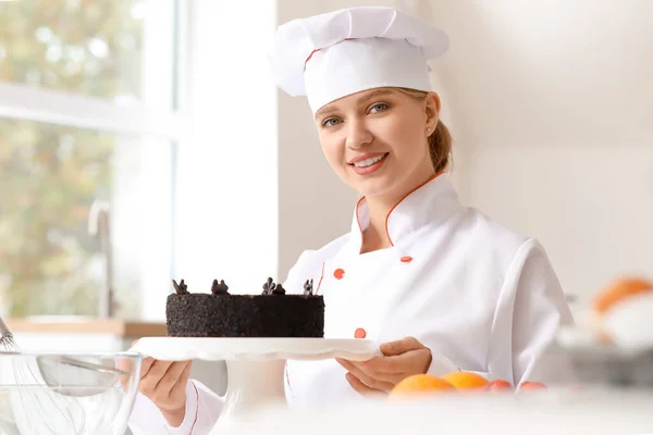 Kobieta cukiernik ze smacznym ciastem w kuchni — Zdjęcie stockowe