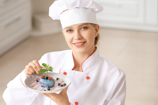 Female confectioner decorating tasty dessert in kitchen