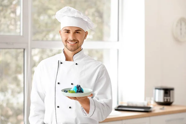 Confeiteiro masculino com sobremesa saborosa na cozinha — Fotografia de Stock