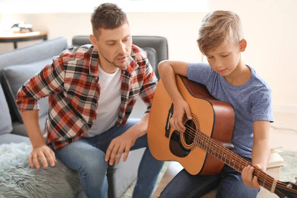 Father teaching his little son to play guitar at home — Stock Photo, Image