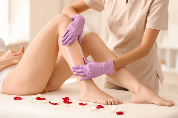 Young woman undergoing epilation of legs in beauty salon — Stock Photo, Image