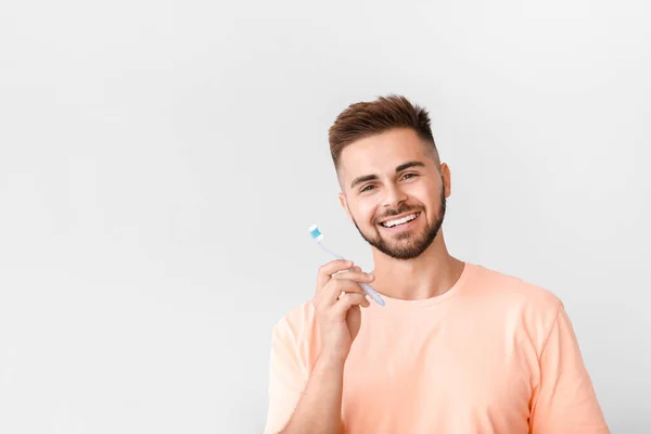 Portret van de mens poetsen tanden op lichte achtergrond — Stockfoto