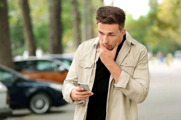 Удивленный молодой человек с мобильным телефоном на улице — стоковое фото