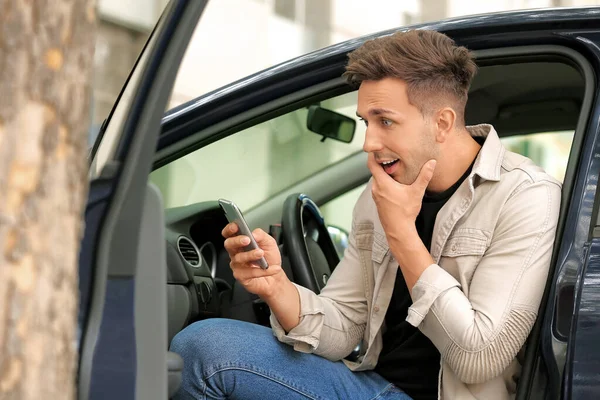 Giovane uomo sorpreso con il cellulare che scende dalla sua auto — Foto Stock