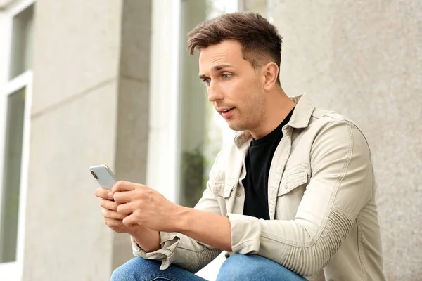 Handsome young man with mobile phone outdoors — Stock Photo, Image