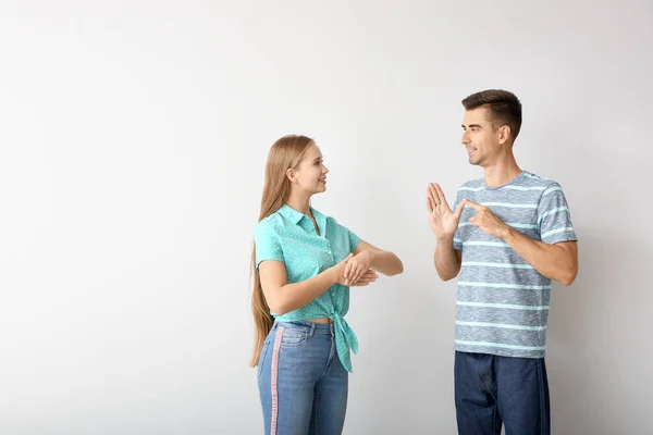 Giovane coppia sordomuta utilizzando il linguaggio dei segni su sfondo bianco — Foto Stock