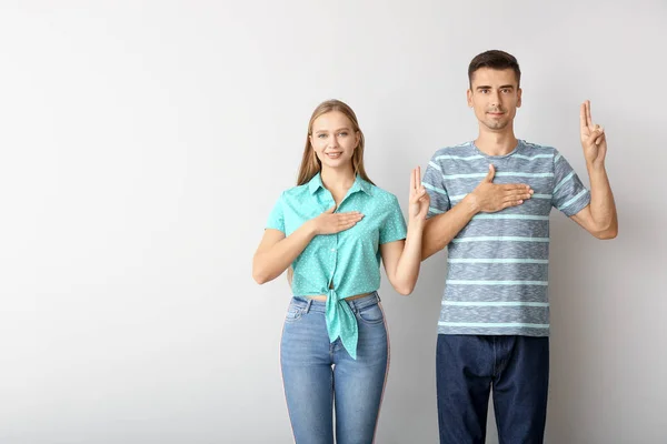 Joven pareja muda sorda usando lenguaje de señas sobre fondo blanco — Foto de Stock