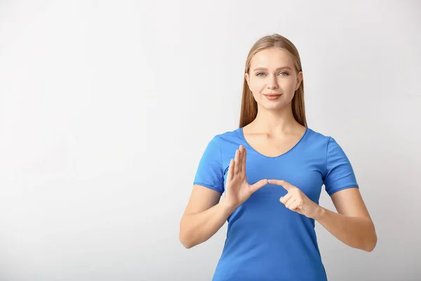 Junge taubstumme Frau mit Gebärdensprache auf weißem Hintergrund — Stockfoto