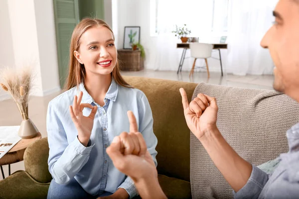 Jovem casal surdo mudo usando linguagem gestual em casa — Fotografia de Stock