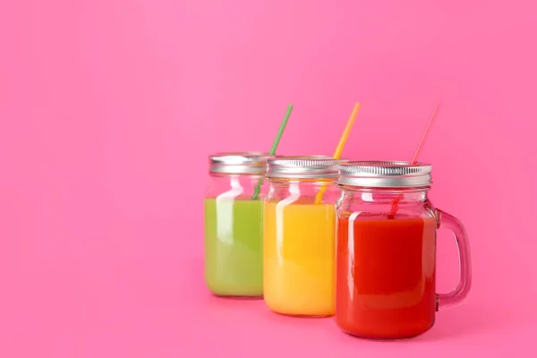 Mason jars of fresh juices on color background — Stock Photo, Image