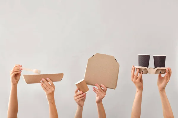 Many hands with containers for food delivery on grey background — Stock Photo, Image