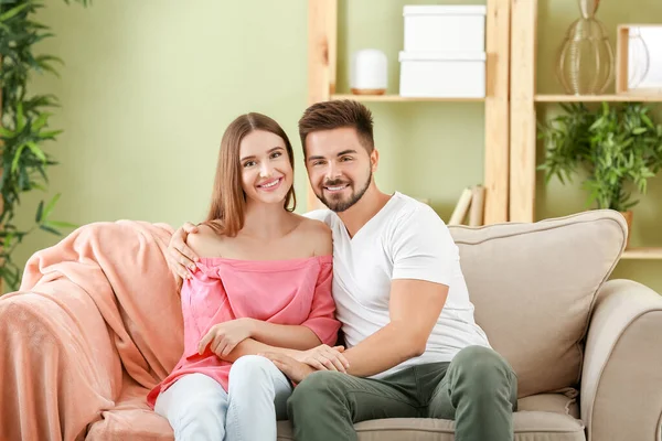 Porträt eines glücklichen jungen Paares, das zu Hause auf dem Sofa sitzt — Stockfoto