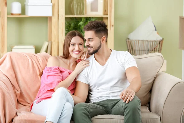 Retrato de jovem casal feliz sentado no sofá em casa — Fotografia de Stock
