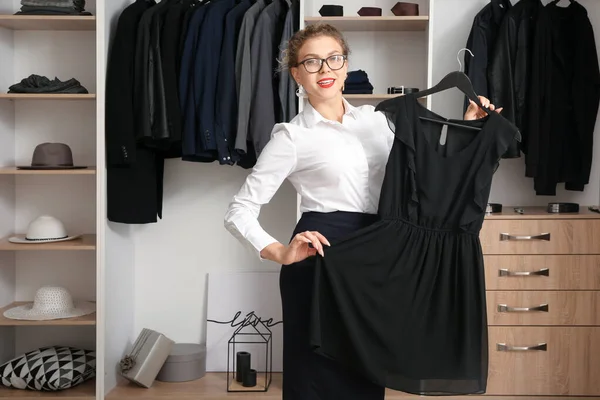 Jeune femme choisissant robe en magasin — Photo