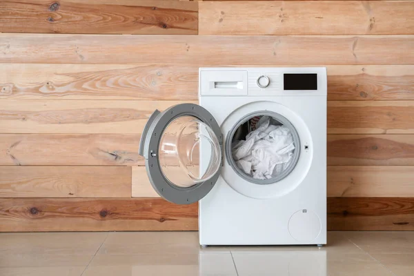 나무 벽 근처에서 빨래를 하고 있는 현대식 세탁기 — 스톡 사진
