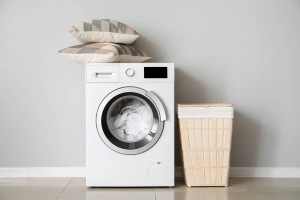 Moderne wasmachine met wasserij in de buurt van witte muur — Stockfoto