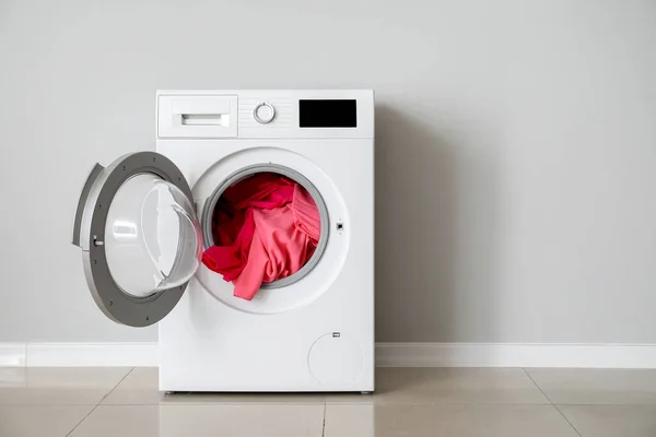 Beyaz duvarın yanında çamaşır makinesi olan modern bir çamaşır makinesi. — Stok fotoğraf