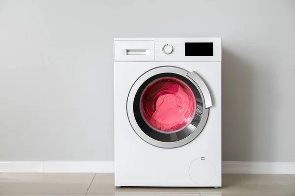 Máquina de lavar roupa moderna com lavanderia perto da parede branca — Fotografia de Stock