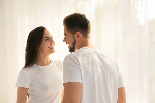 Hermosa pareja joven cerca de la ventana en el dormitorio —  Fotos de Stock