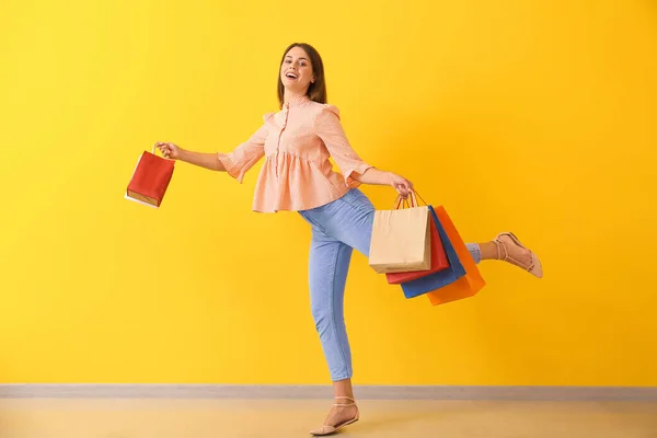 Gyönyörű fiatal nő, bevásárló táskák, színes fal közelében — Stock Fotó