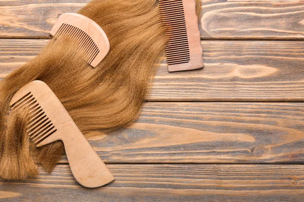 Hair strand and combs on wooden background — Stock Photo, Image