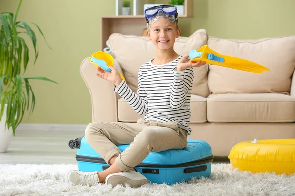 Cute little boy with paddles and mask sitting on suitcase at home — Stock Photo, Image