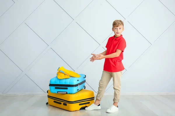 Surprised little boy with luggage near light wall — Stock Photo, Image