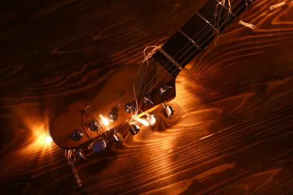 Akoestische gitaar met kerstverlichting op houten achtergrond — Stockfoto