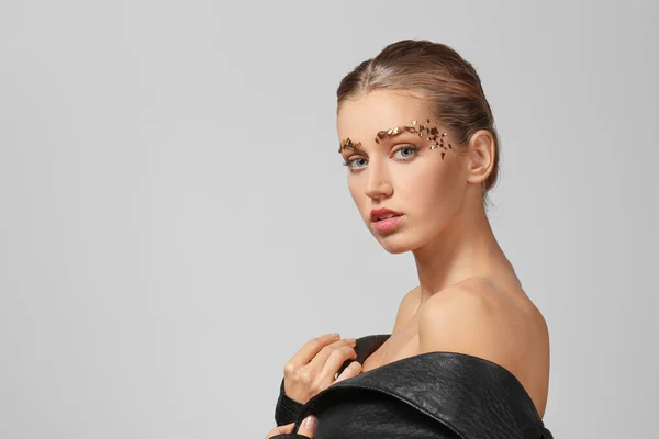 Mujer joven con cejas creativas sobre fondo gris — Foto de Stock