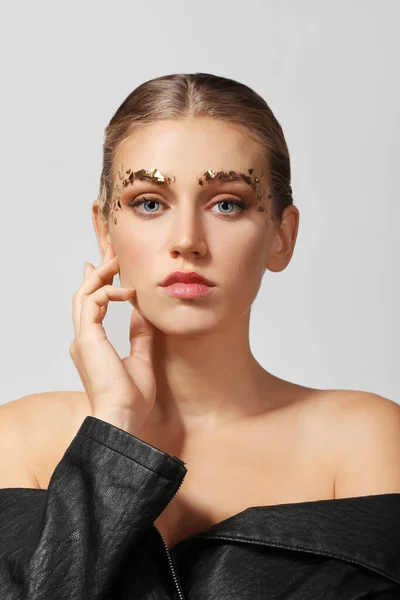 Mujer joven con cejas creativas sobre fondo gris — Foto de Stock
