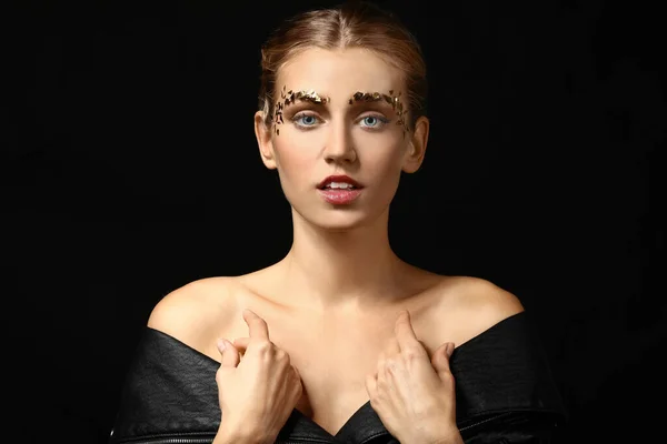 Mujer joven con cejas creativas sobre fondo oscuro — Foto de Stock