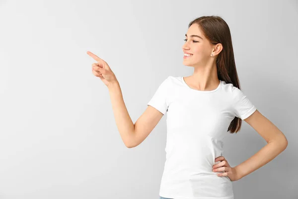 Beautiful teenage girl pointing at something on white background — Stock Photo, Image