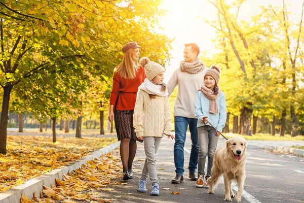 Sonbahar parkında köpekli mutlu bir aile.