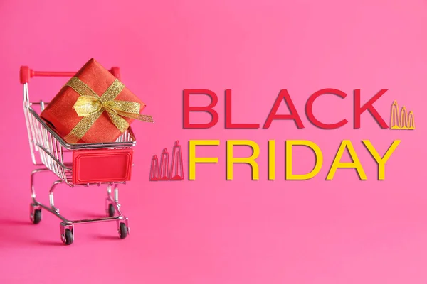 Невеликий кошик з подарунковою коробкою та написом BLACK FRIDAY на кольоровому фоні — стокове фото