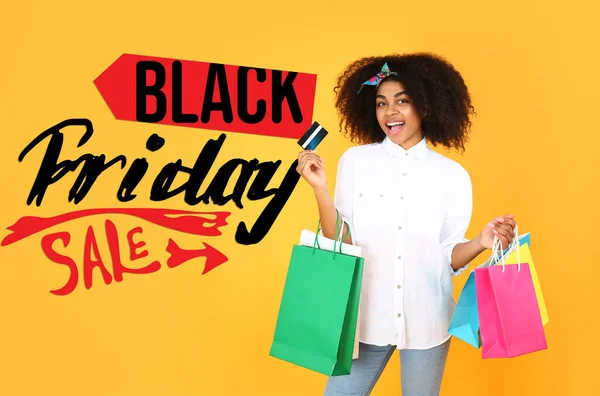 Hermosa mujer afroamericana con bolsas de compras y tarjeta de crédito en el fondo de color. Viernes Negro venta — Foto de Stock