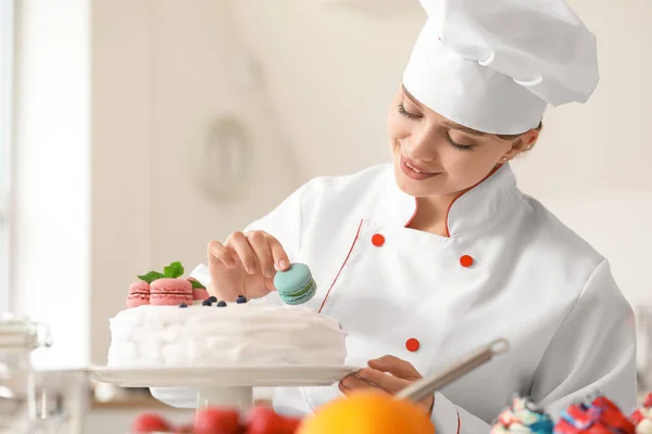 Pastelera femenina que decora sabrosa torta en la cocina — Foto de Stock