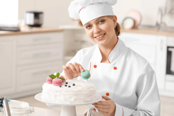 Kobieta cukiernik dekorowanie smaczne ciasto w kuchni — Zdjęcie stockowe