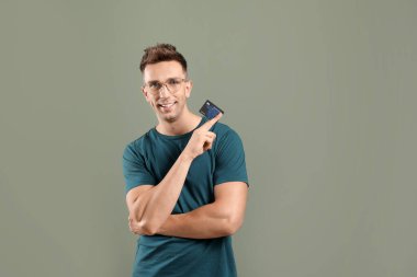 Young man with credit card on color background