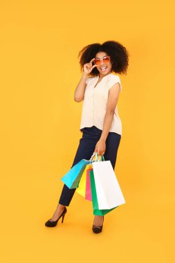Arkaplanda alışveriş torbaları olan güzel Afro-Amerikalı kadın.