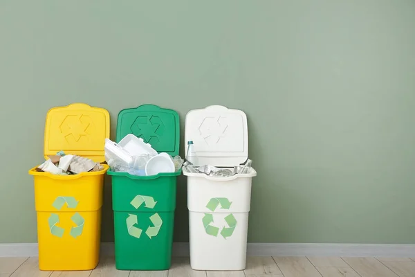Contenedores con diferentes tipos de basura cerca de la pared de color. Concepto de reciclaje — Foto de Stock