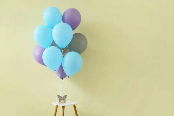 Air balloons with decor on table against color background