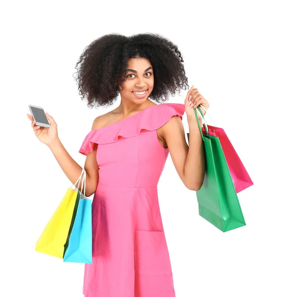 Beautiful African-American woman with shopping bags and mobile phone on white background — Stock Photo, Image