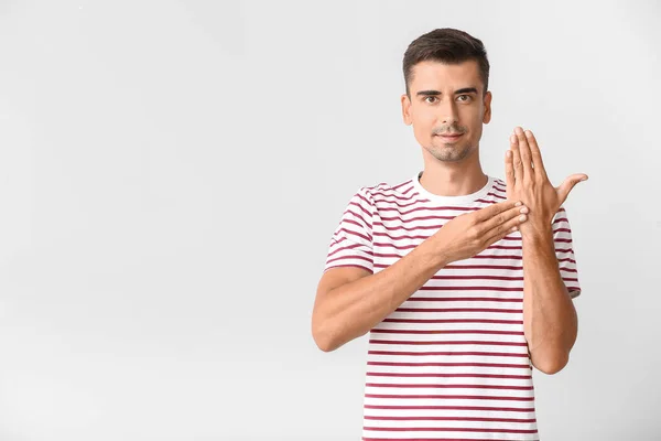 Young deaf mute man using sign language on white background — Stock Photo, Image