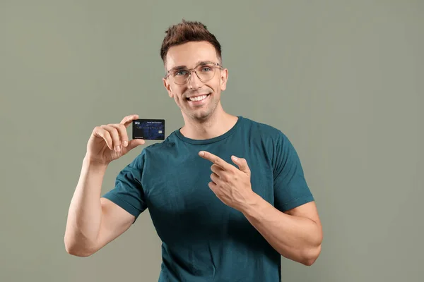 Young man with credit card on color background — Stock Photo, Image