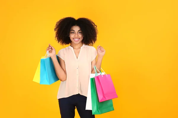 美しいアフリカ系アメリカ人女性でショッピングバッグ上の色背景 — ストック写真